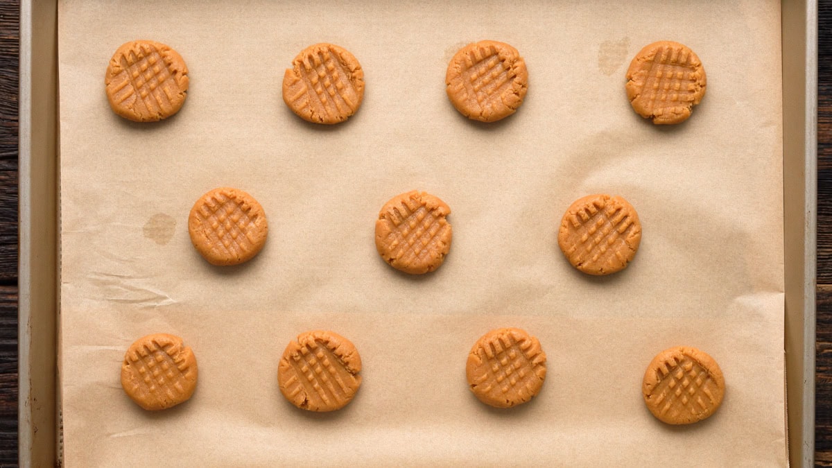 Peanut butter cookie dough balls on a baking sheet before baking.