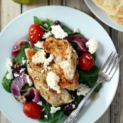 Plate with baked Greek chicken and pita breads on a plate.