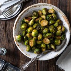 Balsamic Brussels sprouts on a white bowl served on a table.