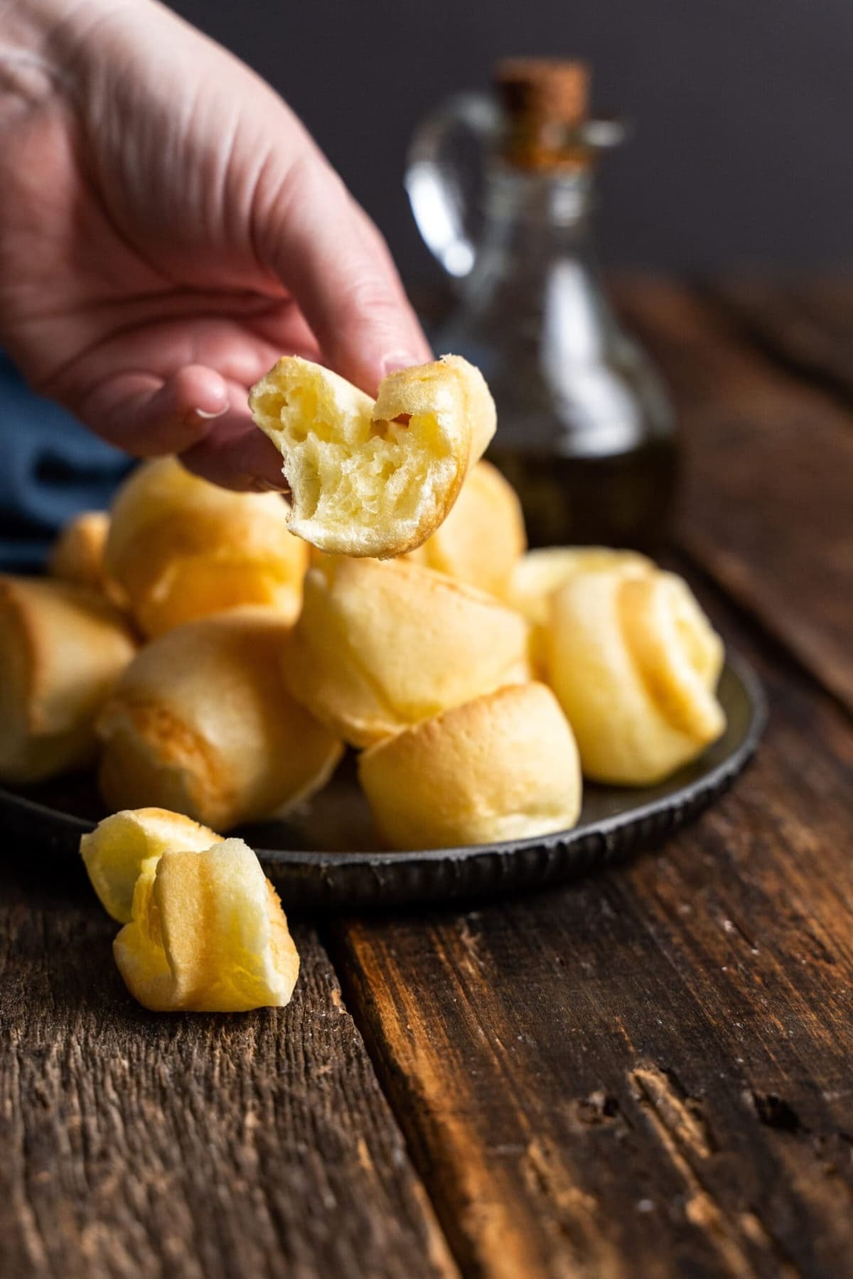 Brazilian cheese bread stacked on a black serving plate.