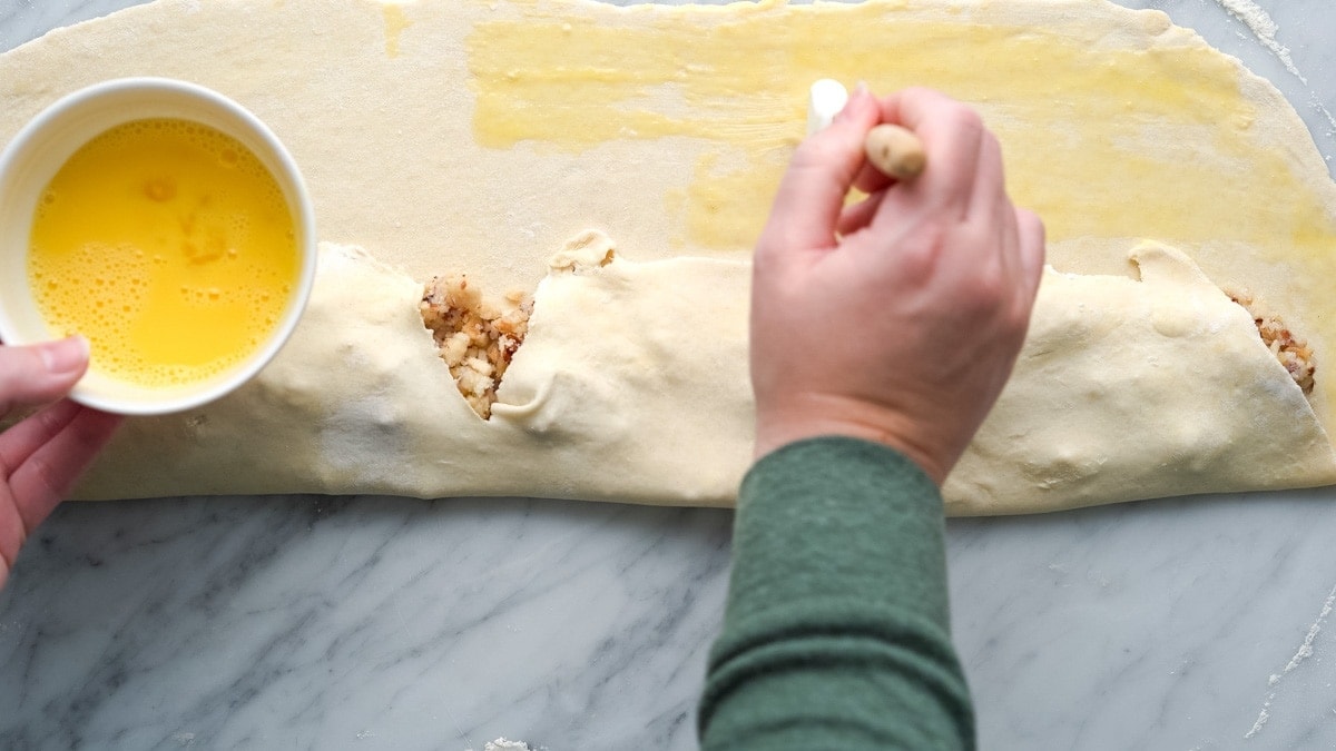 Brushing the folded dough with egg wash.