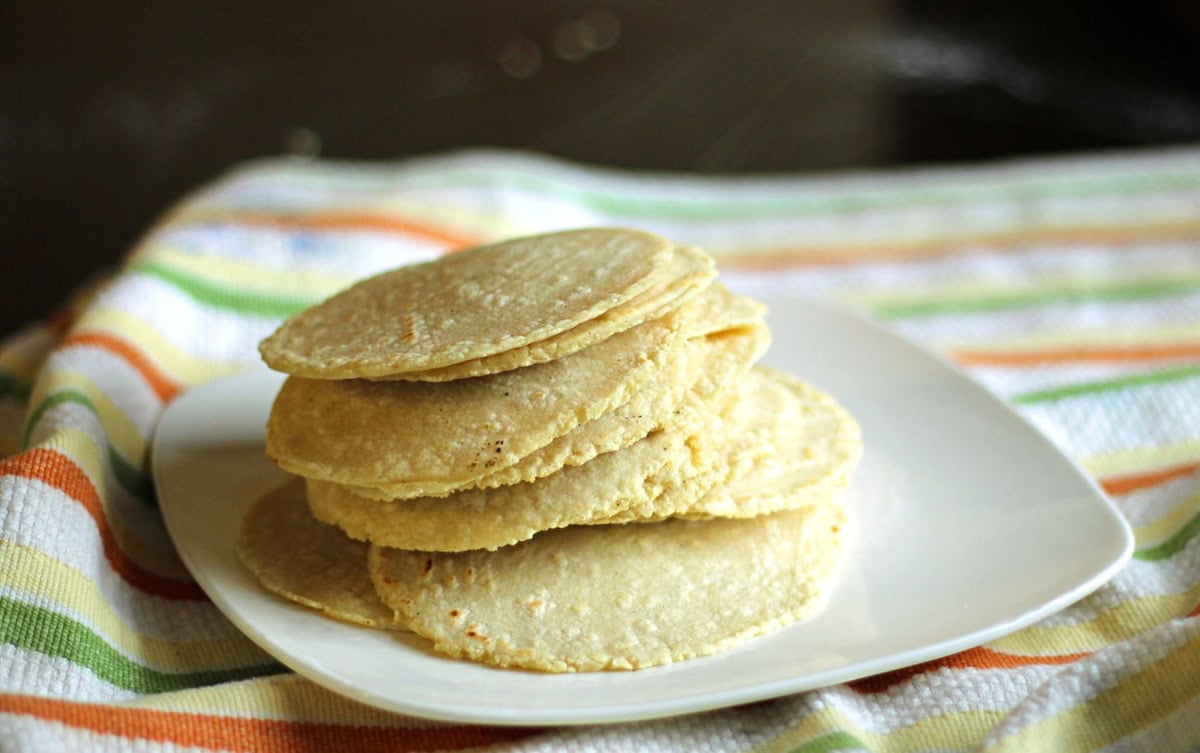 Stacks of Homemade Corn Tortillas on a plate.