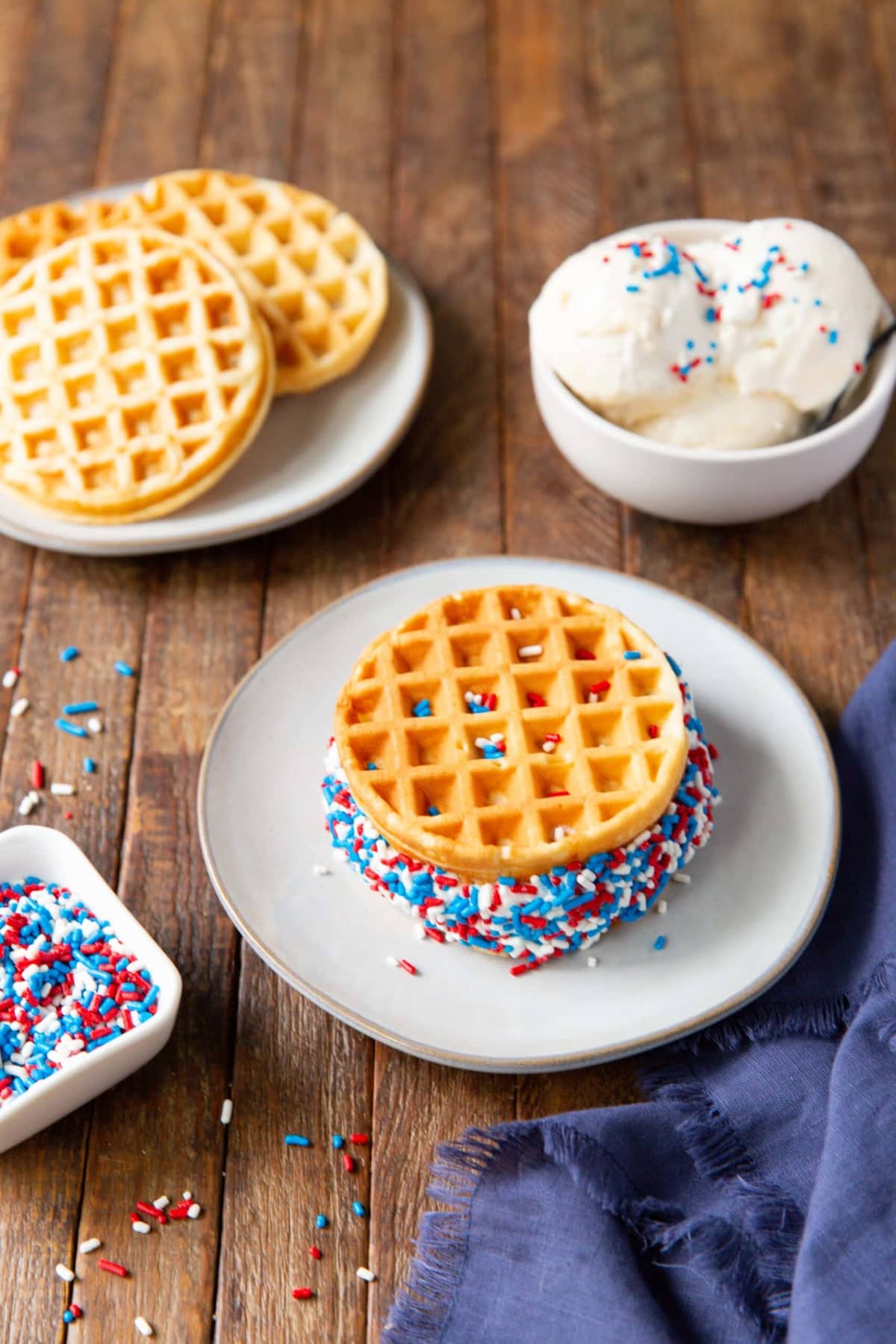 A plate with homemade waffle ice cream sandwiches with colorful toppings.