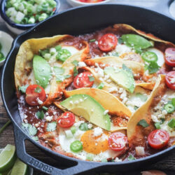 Huevos Rancheros in a cast-iron skillet topped with fresh garnishes.