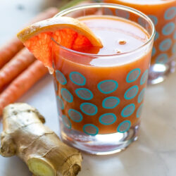 Immune booster juice in a glass with a garnish of a slice of orange served on a table.