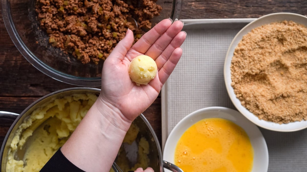 A hand holding a potato ball.
