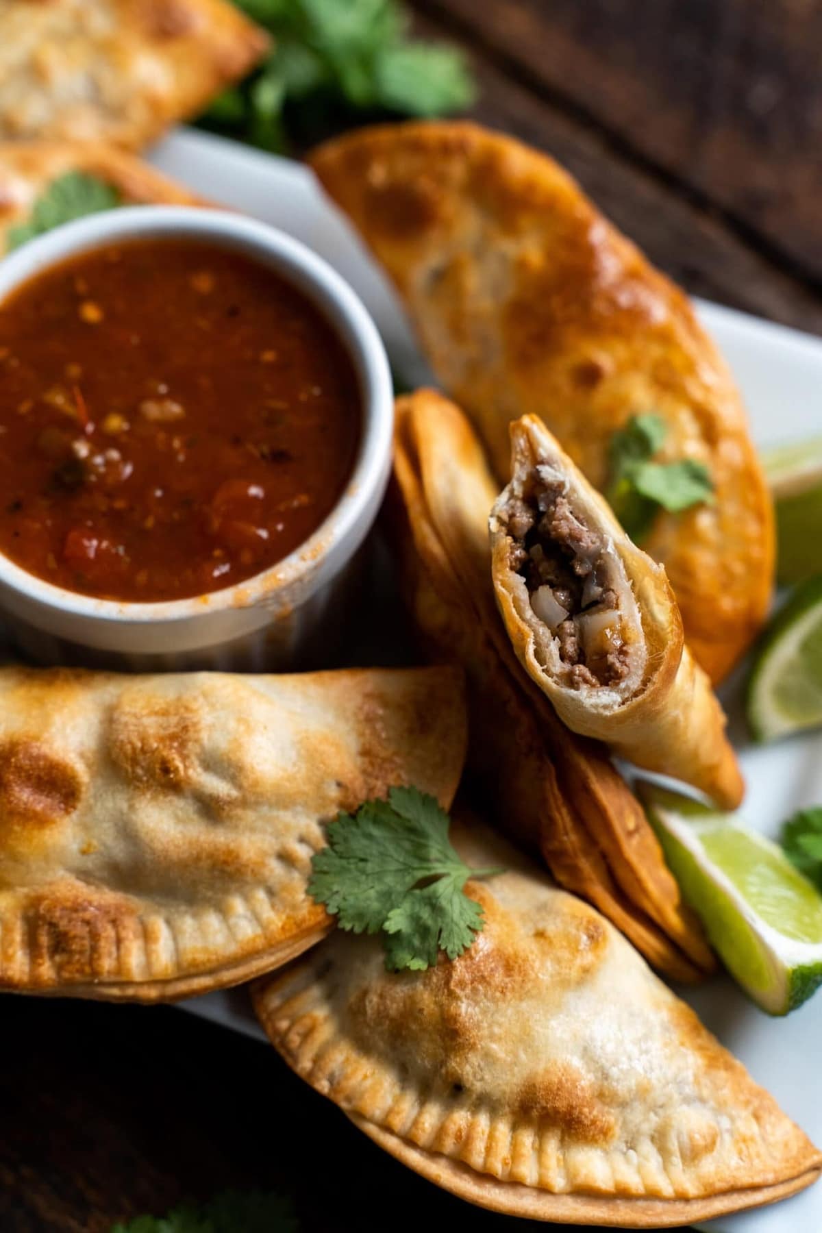 Air fryer empanadas on a white plate with salsa.
