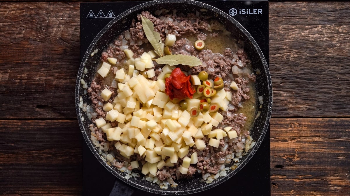 Filling for a Puerto Rican empanada recipe cooking in a skillet.
