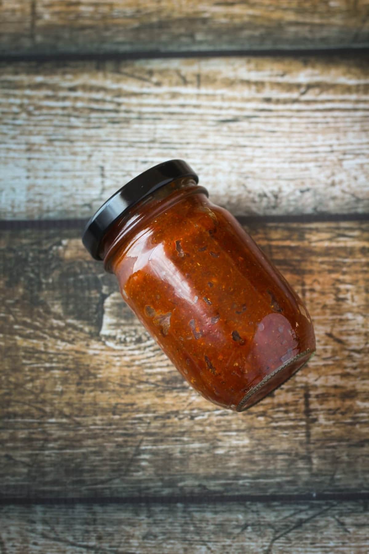 A jar of homemade red curry paste on a table.