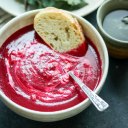 A bowl with roasted beet soup and bread.