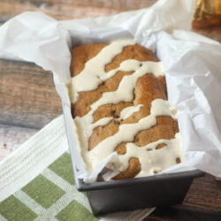 A loaf of spiced pear and pistachio bread drizzled with icing.