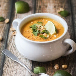 A white bowl of Thai sweet potato carrot soup.